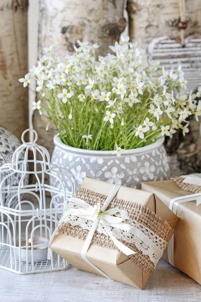 Prachtig ingepakte geschenken en bloemen op de achtergrond — Stockfoto
