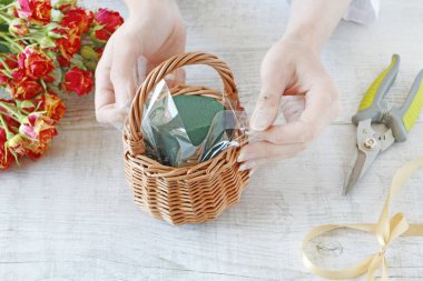 Kadın, güllerin içinde nasıl çiçek aranjmanı yapılacağını gösteriyor.