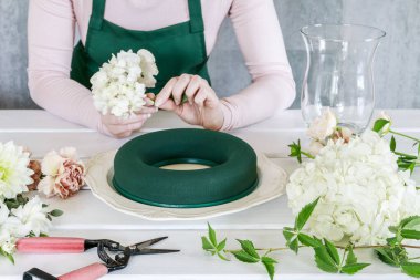 Kadın düğün masasını nasıl çelenkle süsleyeceğini gösteriyor.