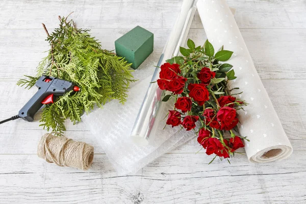 Mujer muestra cómo hacer un arreglo floral con rosas rojas y —  Fotos de Stock