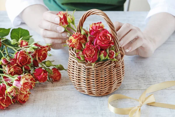 Frau zeigt, wie man ein Blumengesteck mit Rosen im Inneren macht — Stockfoto