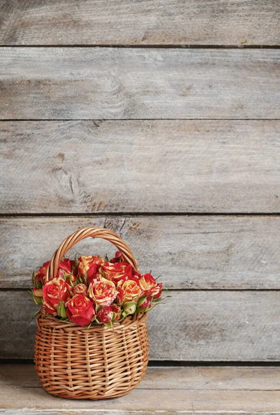 Roses in wicker basket on wooden background. Postcard motif.