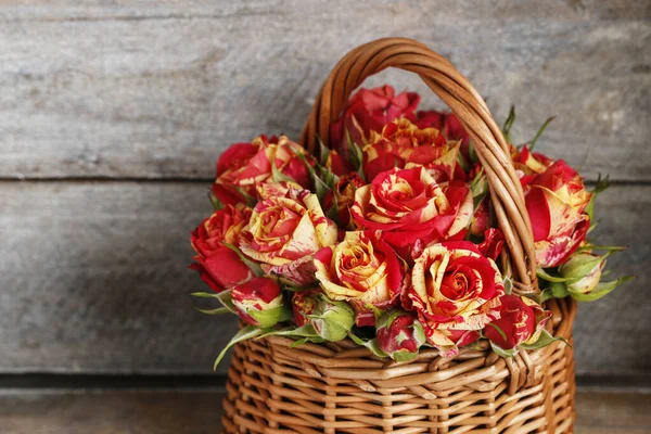 Roses in wicker basket on wooden background. Postcard motif.