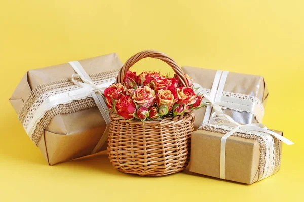 Cesta de mimbre con rosas y regalos bellamente envueltos en amarillo — Foto de Stock