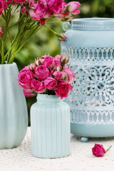 Stół kwiatowy z różowymi różami i romantycznymi latarniami. — Zdjęcie stockowe
