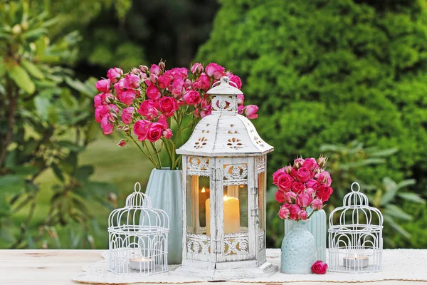 Bloementafel arrangement met roze rozen en romantische lantaarns. — Stockfoto