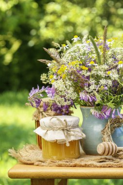 Ballı kavanozlar ve bahçede bir buket yabani çiçek. 