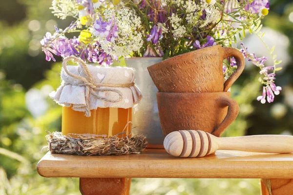 Vasi con miele e bouquet di fiori selvatici in giardino . — Foto Stock