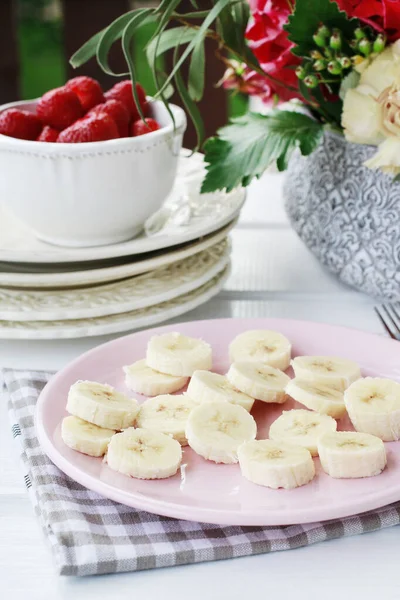 Sliced bananas and ripe strawberries on the table. Bouquet of fl — Stock Photo, Image