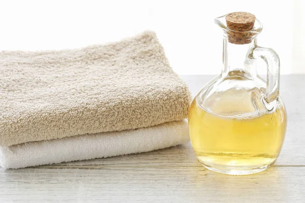 Bottle with golden liquid soap and two towels on the table. — 스톡 사진