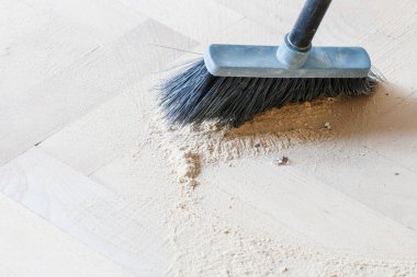 Sweeping a dirty parquet with a traditional brush. Cleaning time clipart