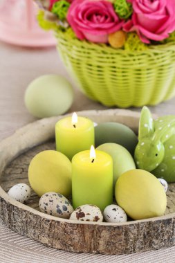 Yeşil mumlar, yumurtalar ve çiçeklerle süslenmiş Paskalya masa süsü. Şenlik zamanı