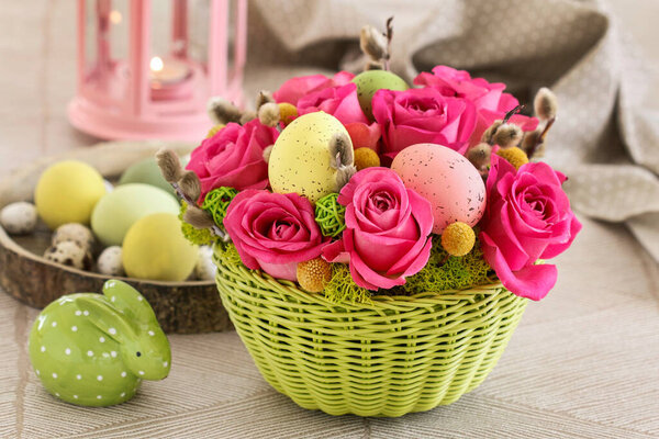 Florist at work: woman shows how to make Easter table decoration with roses, moss and catkins. Step by step, tutorial.