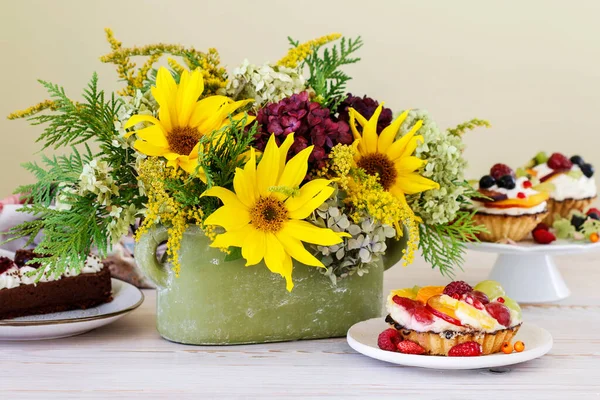 Bunte Cupcakes Und Blumenarrangements Mit Sonnenblumen Und Hortensien Auf Dem — Stockfoto