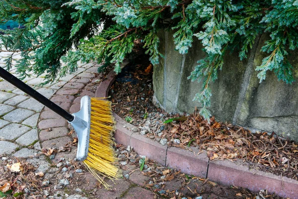 Spring cleaning in the garden. Sweeping dry leaves. Garden hobby