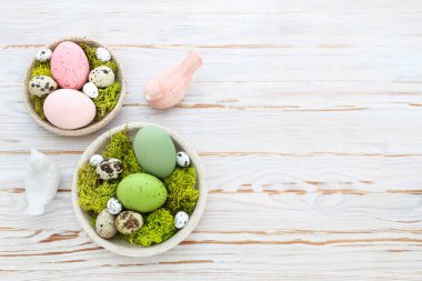 Beyaz ahşap masa üzerinde yumurta, yosun ve seramik heykelciklerle Paskalya süsleri. Şenlik zamanı