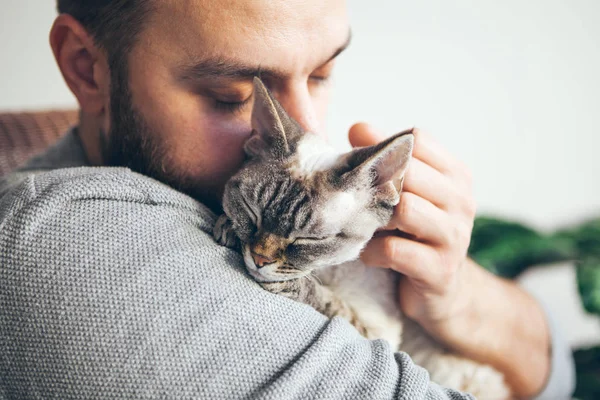 Kedi ve adam, yakın portresi ile mutlu kedi gözleri ve Genç sakallı adam. Yakışıklı genç sarılma ve onun sevimli renk nokta Devon Rex Kitten sarılma. Evcil hayvanlar kavramı