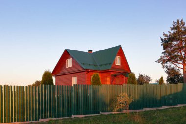 Ahşap ev yeşil metal çatı evinin arkasındaki yeşil çit günbatımı ampullu fotoğraf altında