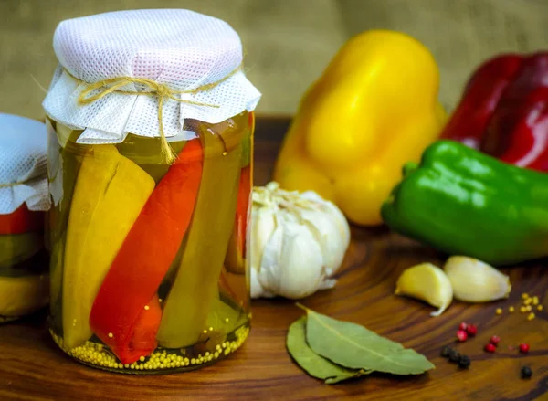 Vejetaryen yiyecekler kavramı korunmuş. Konserve kırmızı, yeşil ahşap arka plan üzerinde bir kavanoza bir sarı biber.