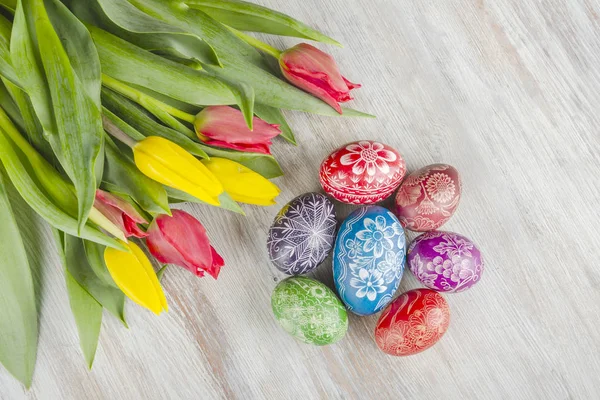 木桌上五颜六色的复活节彩蛋和郁金香花 — 图库照片