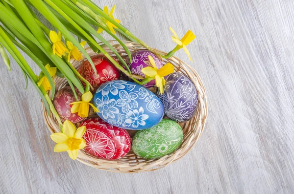 木桌上五颜六色的复活节彩蛋和水仙花 — 图库照片