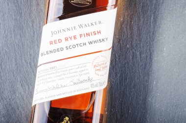 Johnnie Walker 'ın kırmızı çavdarı, harmanlanmış viskiyi taş kaplama arka planda bitirir. Johnnie Walker 1820 'de Kilmarnock, İskoçya' da kuruldu.