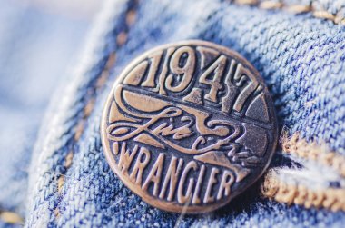 Mavi kot üzerinde Wrangler düğmesinin closeup. Wrangler, Amerikalı kot pantolon üreticisidir. Merkezi Greensboro, North Carolina, ABD'de.