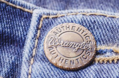 Mavi kot üzerinde Wrangler düğmesinin closeup. Wrangler, Amerikalı kot pantolon üreticisidir. Merkezi Greensboro, North Carolina, ABD'de.