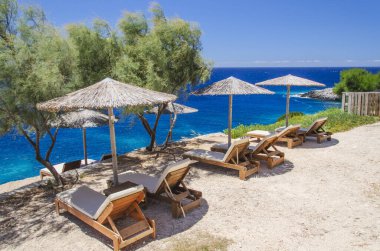 Yunanistan 'ın Zakynthos adasının batı kıyısındaki saman plaj şemsiyeleri ve güneşlikler