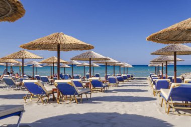 Yunanistan 'ın Zakynthos adasının doğu kıyısında saman plaj şemsiyeleri ve güneş sandalyeleri