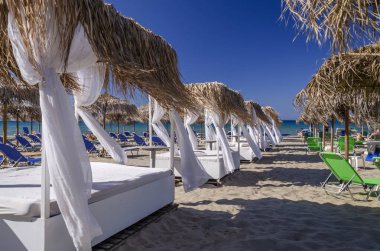 Yunanistan 'ın Zakynthos adasının doğu kıyısında saman plaj şemsiyeleri ve güneş sandalyeleri