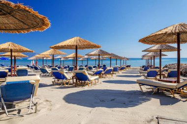 Yunanistan 'ın Zakynthos adasının doğu kıyısında saman plaj şemsiyeleri ve güneş sandalyeleri