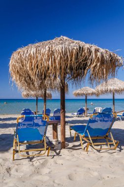 Yunanistan 'ın Zakynthos adasının doğu kıyısında saman plaj şemsiyeleri ve güneş sandalyeleri