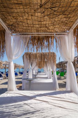 Yunanistan 'ın Zakynthos adasının doğu kıyısında saman plaj şemsiyeleri ve güneş sandalyeleri