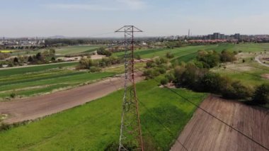 Tarım arazisindeki elektrik direkleri ve yüksek voltaj hatları. Yüksek voltaj direkleri. Elektrik iletim hattı 4K, UHD, Sinematik, Hava Görüntüleri