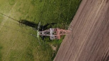 Tarım arazisindeki elektrik direkleri ve yüksek voltaj hatları. Yüksek voltaj direkleri. Elektrik iletim hattı 4K, UHD, Sinematik, Hava Görüntüleri