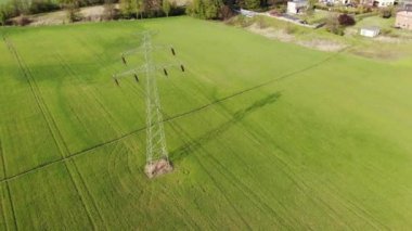 Tarım arazisindeki elektrik direkleri ve yüksek voltaj hatları. Yüksek voltaj direkleri. Elektrik iletim hattı 4K, UHD, Sinematik, Hava Görüntüleri