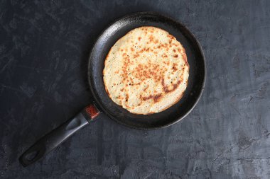 Siyah arka planda siyah bir tavada lezzetli bir krep.