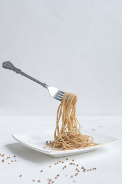 Beyaz bir masada karabuğdaydan yapılmış spagetti.