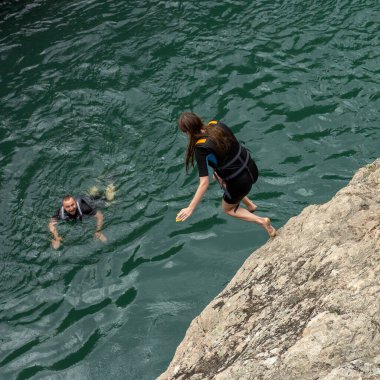  Maikop, Respublika Adygeya, Rusya Federasyonu, 08.16.2020: Su raftingi katılımcıları, bir yaz günü, bir dağ nehri üzerinde, kayalık kıyıdan suya atlıyor.