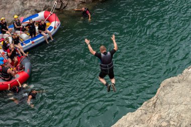  Maikop, Respublika Adygeya, Rusya Federasyonu, 08.16.2020: Su raftingi katılımcıları, bir yaz günü, bir dağ nehri üzerinde, kayalık kıyıdan suya atlıyor.
