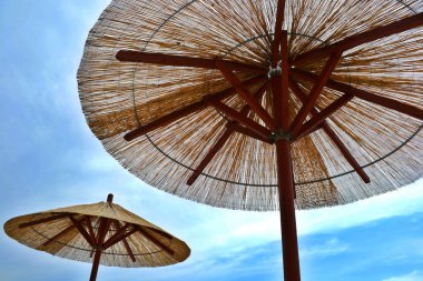 Reed plaj şemsiyeleri mavi gökyüzü ve bulutlar. Yakın çekim görünümü.