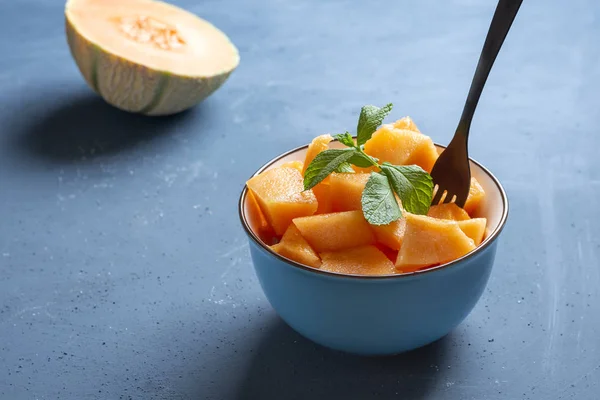 Fresh melon cut into pieces in a bowl and background blue - image