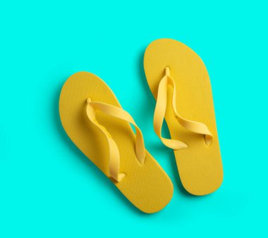 Turkuaz arka planda sarı plaj terlikleri. yaz konsepti