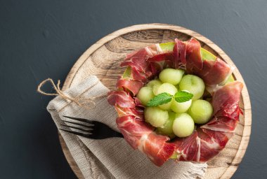 Kurutulmuş jambonlu kavun, fotokopi alanı olan rustik arka plan. en üstteki görünüm