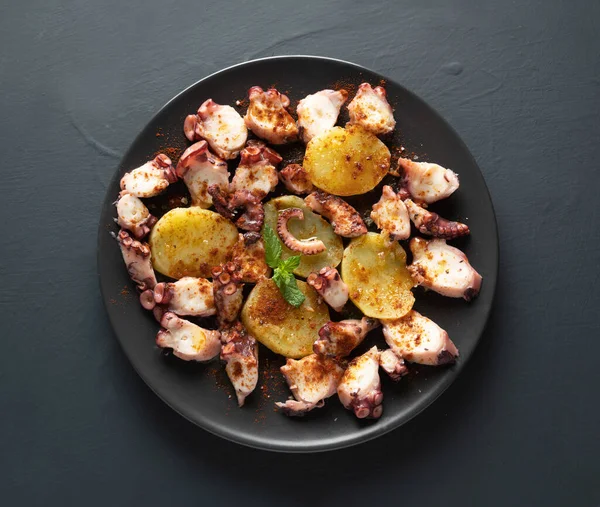 cooked octopus presented sliced with potatoes, and rustic background. top view