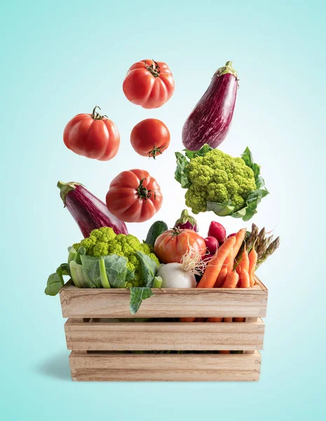 Wooden box with flying vegetables, on blue background