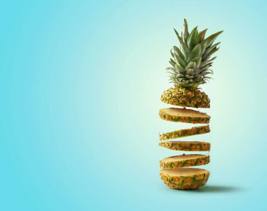 Dilimlere ayrılmış taze ananas uçuyor, mavi arkaplandan kopyalanmış boşluk ile izole edilmiş.