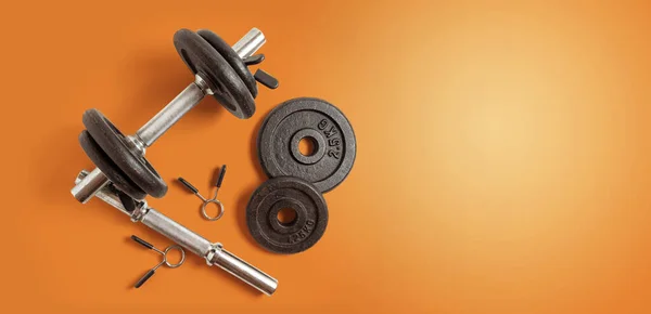 Metal dumbbell set. Isolated on orange background. Gym, fitness and sports equipment symbol. top view. space copy