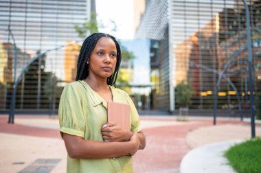 İş kadını elinde tabletle ofis binalarının yanında dikilirken gözlerini kaçırıyor.